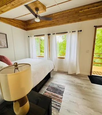 a bedroom with a bed and two windows at Cedar Haven Cabins and Resort in Clearwater
