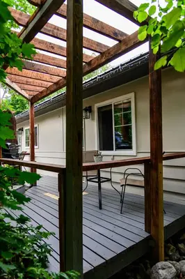 a wooden deck with a pergola and a table at Barefoot Villas and Retreat in Christina Lake