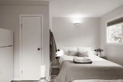a white bedroom with a bed and a window at Barefoot Villas and Retreat in Christina Lake
