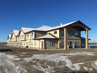 a building in a parking lot with snow on the ground at Westwood Inn in Drayton Valley