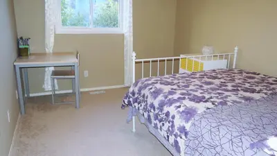 a bedroom with a bed and a table and a window at Brother Li Homestay in Calgary