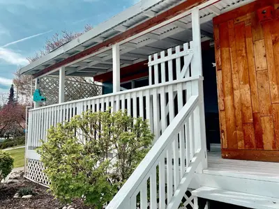 a white porch with a wooden door and a bush at Peachland Beach Resort in Peachland