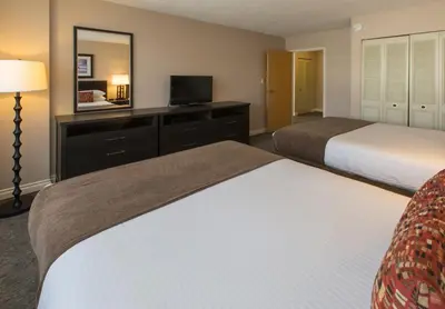 a hotel room with two beds and a mirror at The Embassy Inn in Victoria