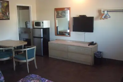 a living room with a tv and a table and a kitchen at Trailside Inn in Lloydminster