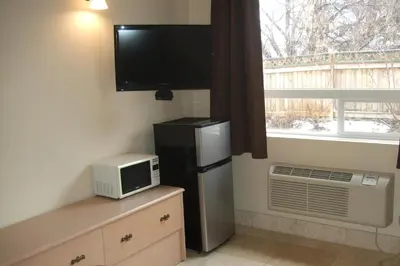 a kitchen with a refrigerator and a tv and a window at Trailside Inn in Lloydminster