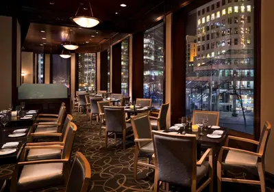 a restaurant with tables and chairs and a large window at Hyatt Regency Vancouver in Vancouver