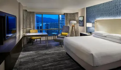a hotel room with a bed and a desk and a window at Hyatt Regency Vancouver in Vancouver