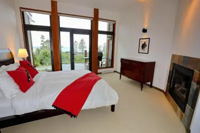 a bedroom with a bed with red pillows and a fireplace at Oceanview Condo - Pacific Rim Retreat in Ucluelet