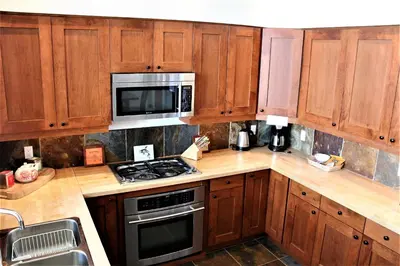 a kitchen with wooden cabinets and a stove and microwave at Oceanview Condo - Pacific Rim Retreat in Ucluelet
