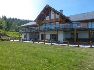 a large wooden house with a lawn in front of it at Little Black Bear Lodge/B&B in Bridge Lake