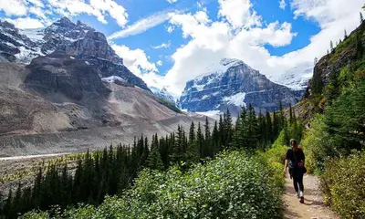 a woman walking down a trail in the mountains at Eleven Revelstoke Lodge in Revelstoke