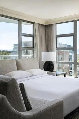 a bedroom with a bed and a couch and windows at Victoria Marriott Inner Harbour in Victoria