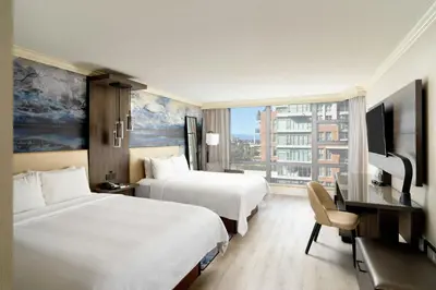 a hotel room with two beds and a desk and a television at Victoria Marriott Inner Harbour in Victoria