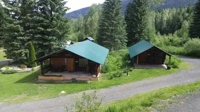 two small wooden cabins in a field with trees at Wolfwood Guest Ranch in Clearwater