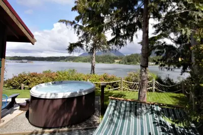 a hot tub on a patio with a view of a lake at Private Oceanfront Cabin With Hot Tub Doc Holiday Cabin in Ucluelet