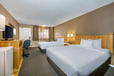 a hotel room with two beds and a desk at Econo Lodge Inn & Suites in North Vancouver