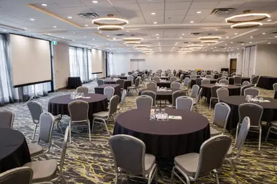 a conference room with tables and chairs and a screen at Holiday Inn Hotel & Suites Calgary South - Conference Ctr by IHG in Calgary