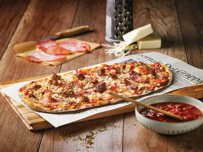 two pizzas on a wooden table with a bowl of sauce at Holiday Inn Hotel & Suites Calgary South - Conference Ctr by IHG in Calgary