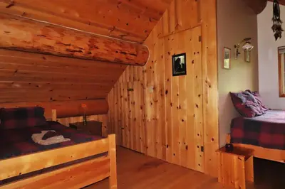 a bedroom with two beds in a log cabin at Rocky Ridge Resort-BC in Smithers