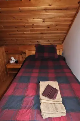 a bed in a room with a wooden ceiling at Rocky Ridge Resort-BC in Smithers