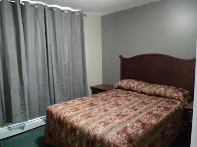 a bedroom with a bed and a window with curtains at Aries Motel in Edson