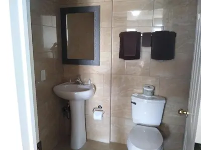 a bathroom with a toilet and a sink and a mirror at Aries Motel in Edson