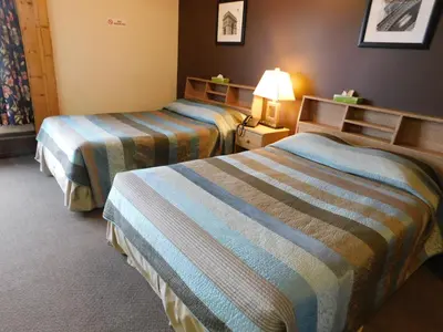 a hotel room with two beds and a lamp at Timberland Hotel in Hinton