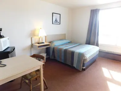 a hotel room with a bed and a desk and a table at Timberland Hotel in Hinton