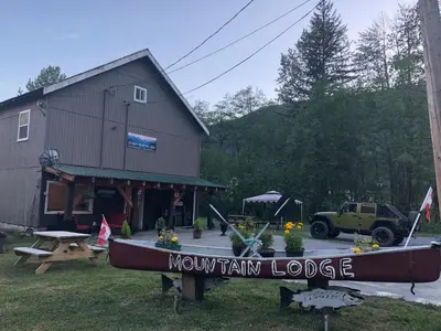 a brown train lodge with a boat in front of it at Stewart Mountain Lodge in Stewart