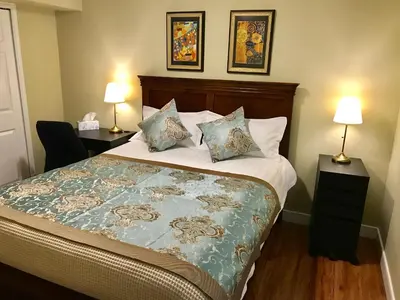 a bedroom with a bed with two lamps and two tables at Bay View House in Vancouver