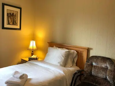 a bedroom with a bed and a chair and a lamp at Cozy Bedrooms Guest House in Vancouver