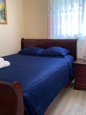 a bedroom with a bed with blue sheets and a window at Richmond Vancouver Airport Comfy Home in Richmond