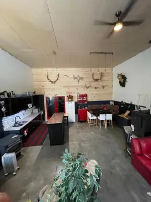 a living room with a red couch and a table at Nanimahoo's Sled N'Bed in Malakwa