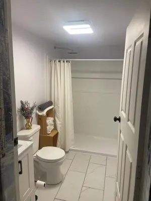 a white bathroom with a toilet and a shower at Nanimahoo's Sled N'Bed in Malakwa