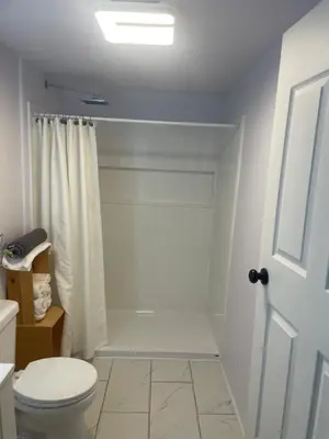 a white bathroom with a toilet and a shower at Nanimahoo's Sled N'Bed in Malakwa