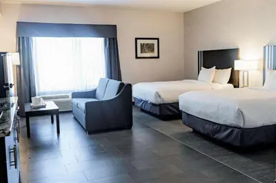 a hotel room with two beds and a chair at Park Inn by Radisson Edmonton Airport in Leduc