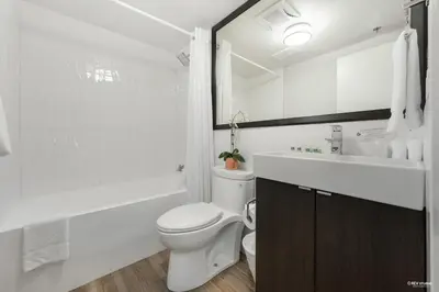 a white bathroom with a toilet and a sink at Queens Hotel in New Westminster