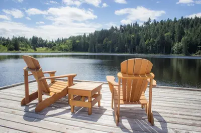 two chairs and a table on a dock near a lake at The Cottages on Salt Spring Island in Ganges