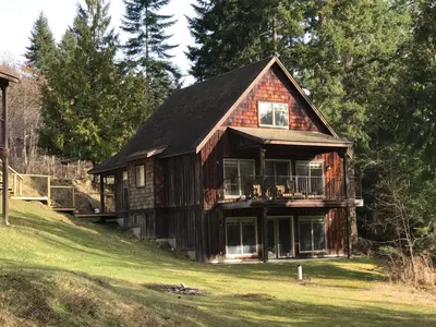 a large wooden house on a hill with trees at The Cottages on Salt Spring Island in Ganges