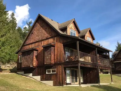 a large wooden house with a balcony at The Cottages on Salt Spring Island in Ganges
