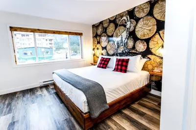a bedroom with a bed and a wall of logs at Crash Hotel Squamish in Squamish
