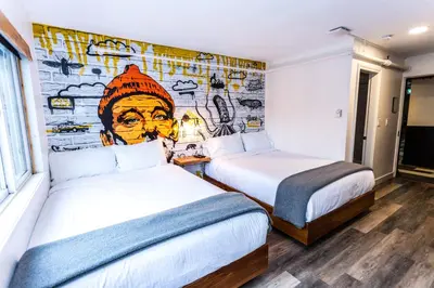 two beds in a room with a mural at Crash Hotel Squamish in Squamish