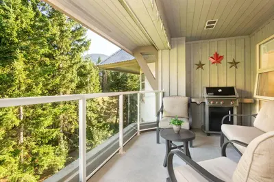 a screened in porch with chairs and a fireplace at Aspens Mountain Side Resort in Whistler