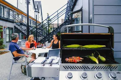 a group of people sitting at a table with a grill at Basecamp Resorts Canmore in Canmore