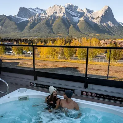 a man and woman in a jacuzzi tub with mountains at Basecamp Resorts Canmore in Canmore
