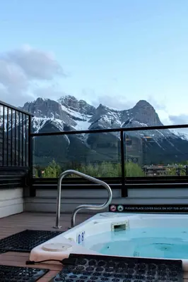 a hot tub on a balcony with a view of mountains at Basecamp Resorts Canmore in Canmore