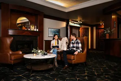 a man and woman sitting in a room with a fireplace at Chateau Jasper in Jasper