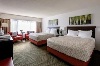 a hotel room with two beds and a chair and a table at Chateau Jasper in Jasper