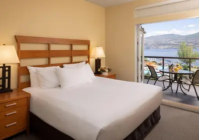 a bedroom with a large bed and a balcony at The Cove Lakeside Resort in West Kelowna