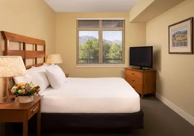 a bedroom with a white bed and a television at The Cove Lakeside Resort in West Kelowna